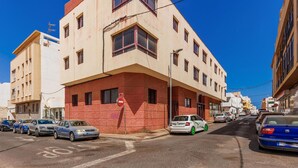 Una vista di strada con un edificio con facciata in mattoni rossi e numerose finestre. Automobili sono parcheggiate lungo la strada, ed è visibile un segnale di divieto di accesso.