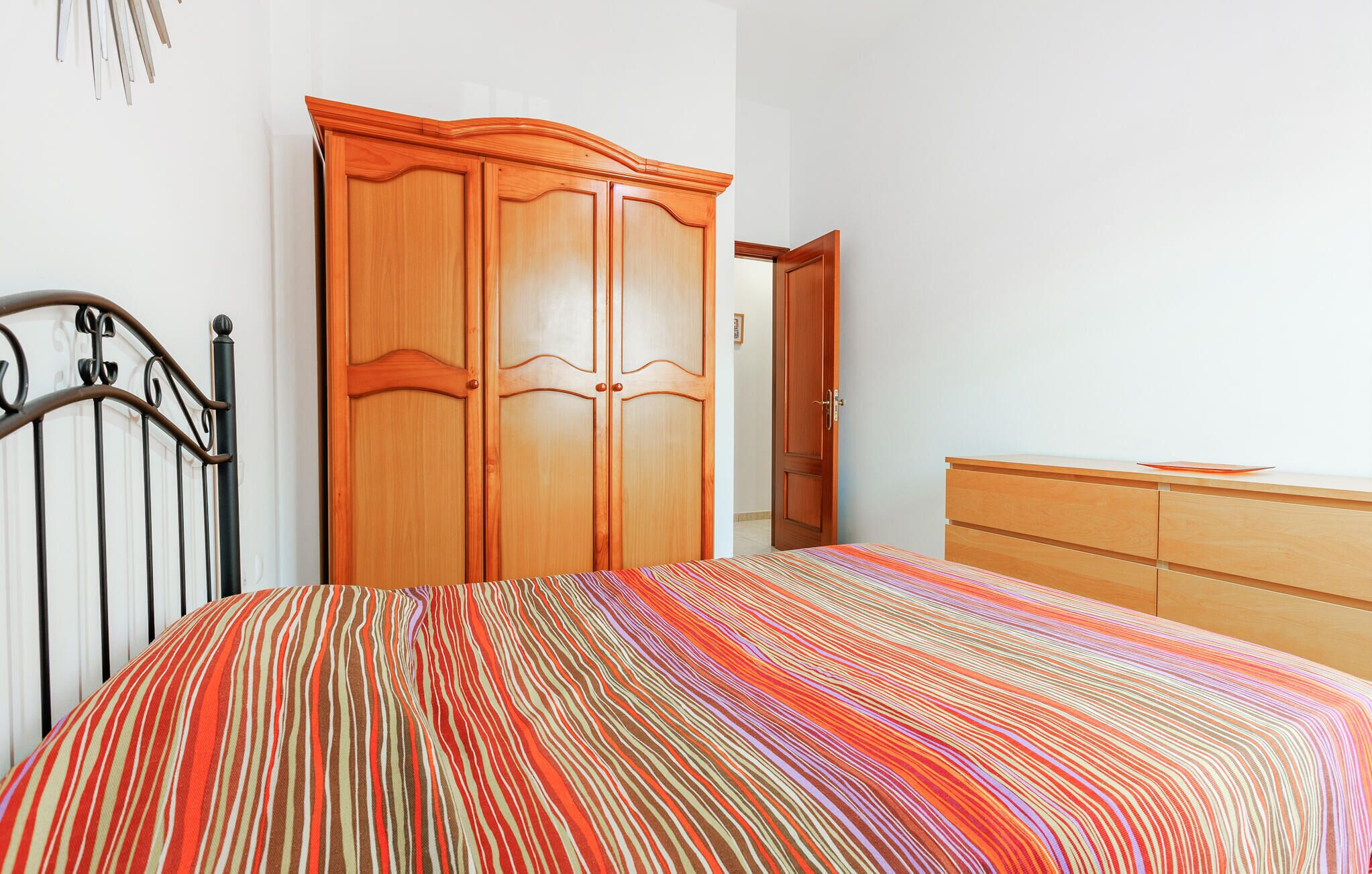 Un dormitorio con una cama, un armario de madera y un aparador.