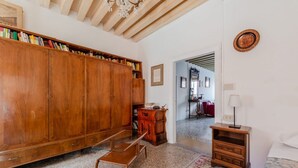 A room with a wooden bookcase, a small wooden table, a bench, and a patterned rug.