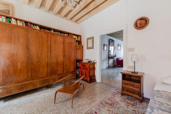 Una habitación con una biblioteca de madera, una pequeña mesa de madera, un banco y un tapete estampado.