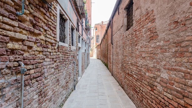 A narrow alleyway with brick walls and a paved path.