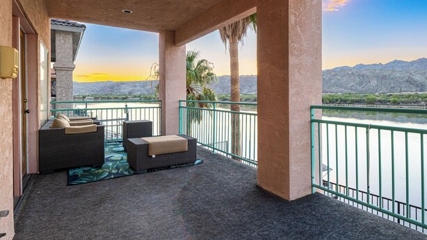 A balcony with wicker furniture, a view of mountains, and a body of water. - Bullhead City Riverfront Home with Dock! (Bullhead City)