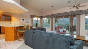 A spacious living area with a grey sofa, wooden dining table, and a view of the outdoors. - Bullhead City Riverfront Home with Dock! (Bullhead City)
