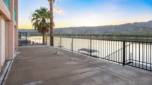 A balcony with a concrete floor, a metal railing, and a view of a river and mountains. - Bullhead City Riverfront Home with Dock! (Bullhead City)