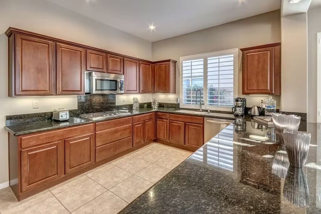 A spacious kitchen with dark granite countertops, wooden cabinets, and a large island.