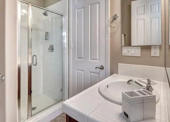 Une salle de bain moderne avec une douche à parois de verre, un meuble-lavabo blanc et un miroir au-dessus du lavabo.