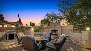 An outdoor patio with wicker furniture, a grill, and a fireplace. - Lux Desert Oasis w/ saltwater pool near Coachella (Indio)