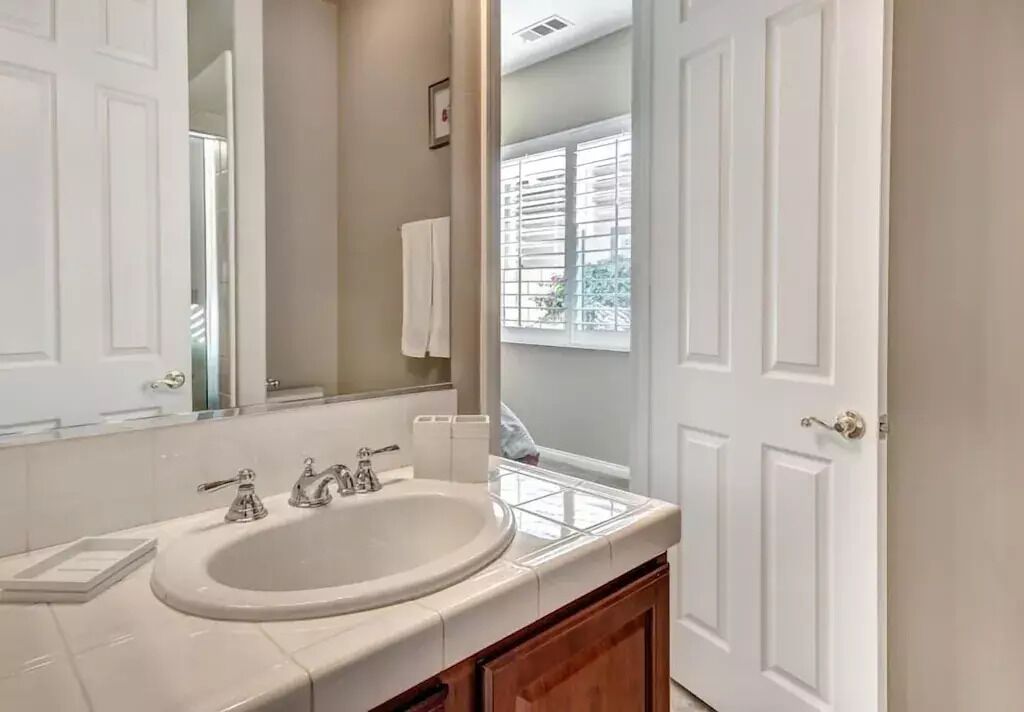 A bathroom with a white sink, mirror, and wooden cabinets.