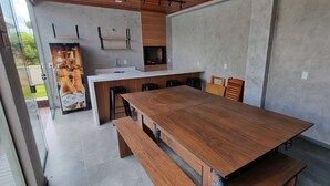 Une cuisine moderne avec une table en bois et des tabourets de bar, un four encastré et une grande fenêtre donnant sur un jardin.