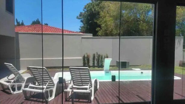 Un espace aménagé au bord de la piscine, avec des chaises longues et une petite cascade décorative.