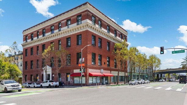 A red brick building with a flat roof and a corner entrance.