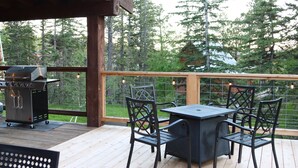 Eine Terrasse im Freien mit Grill, Tisch und Stühlen.