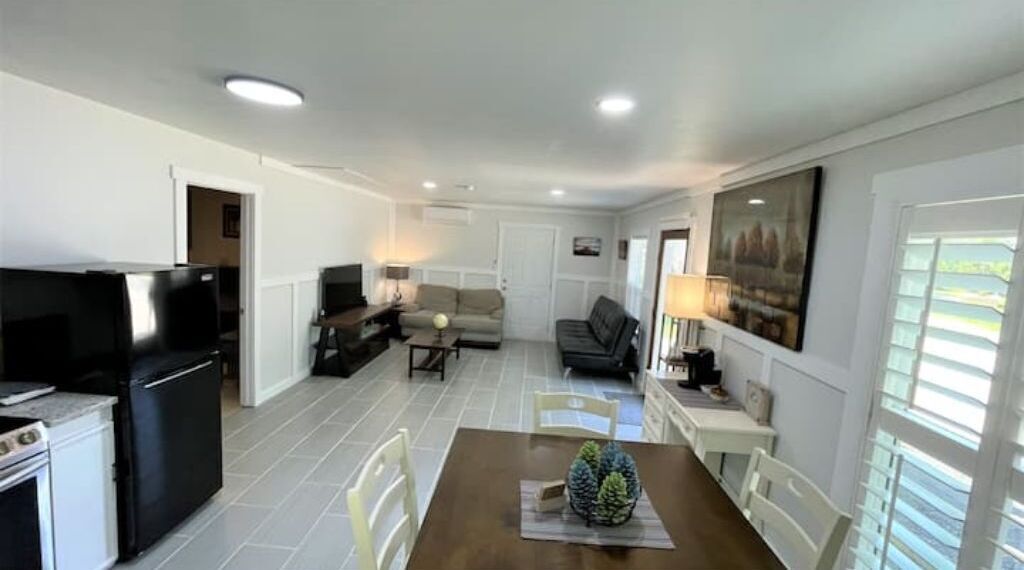 A spacious living area with a dining table, chairs, a sofa, and a television.