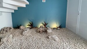 A room with a blue wall, a staircase, and a white door. There are rocks and plants on the floor. - Comfortable Studio, Great location+AA+WiFi 60MB+Kitchen
 (Cancún)