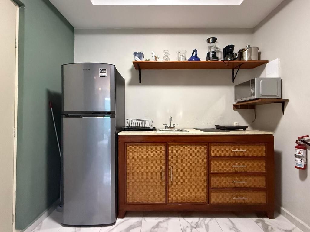 A compact kitchen with a refrigerator, microwave, and wooden cabinets.