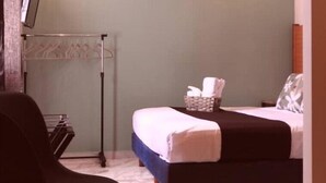 A hotel room with a bed, a small table, a chair, a coat rack, and a basket with towels. - Comfortable Studio, Great location+AA+WiFi 60MB+Kitchen
 (Cancún)