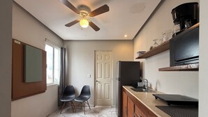 Una cucina compatta con ventilatore a soffitto, frigorifero, macchina del caffè e lavello.