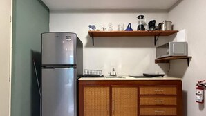 A compact kitchen with a refrigerator, microwave, and wooden cabinets. - Outstanding Loft AC, WiFi 60MB, Kitchen, Bathroom
 (Cancún)