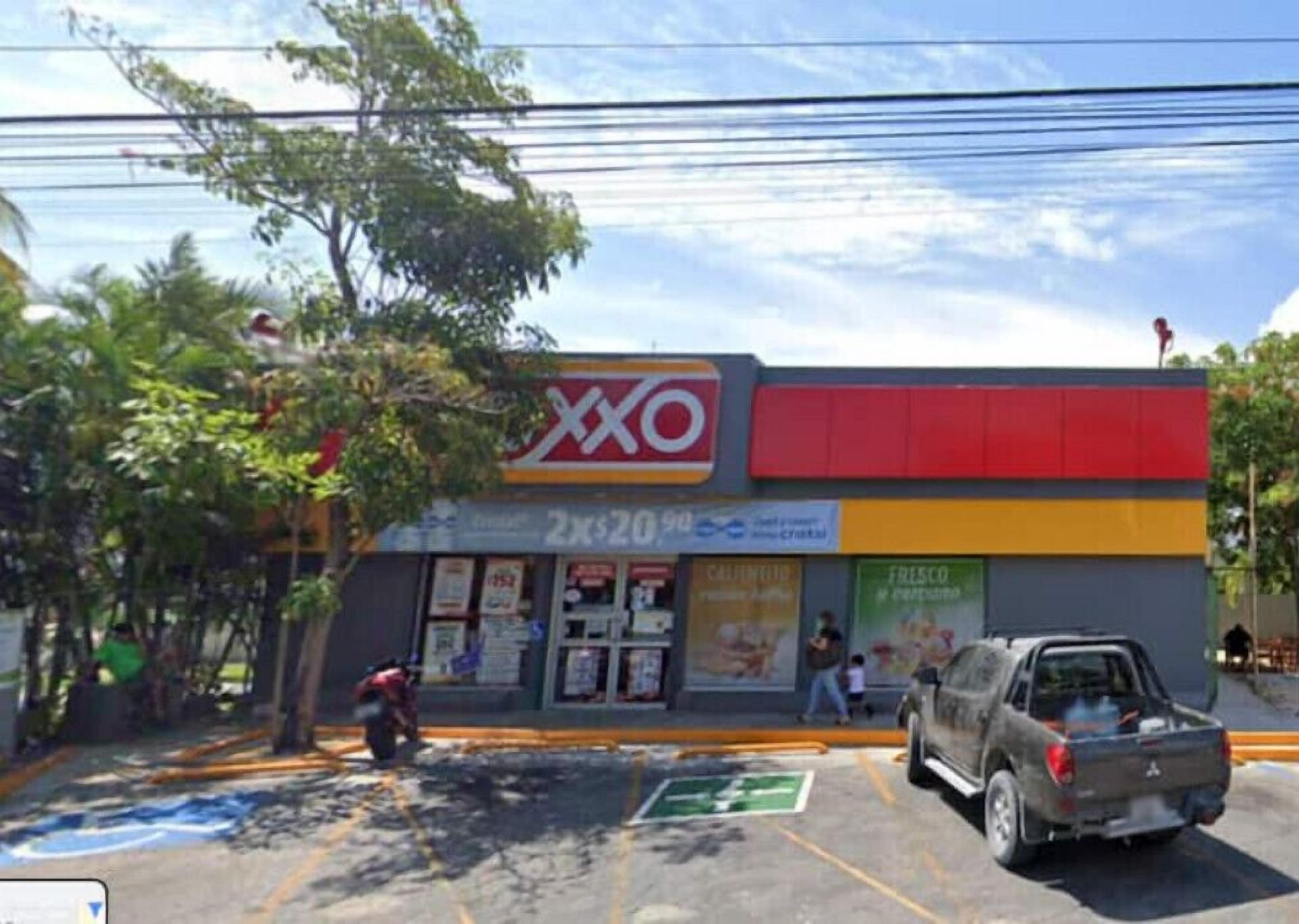 A commercial building with a large 'XXO' sign, a parking lot, and a few people nearby.