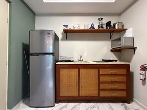 Una cocina compacta con refrigerador, microondas y armarios de madera.
