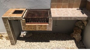 Una griglia da esterno con base in pietra e schienale rivestito di piastrelle.