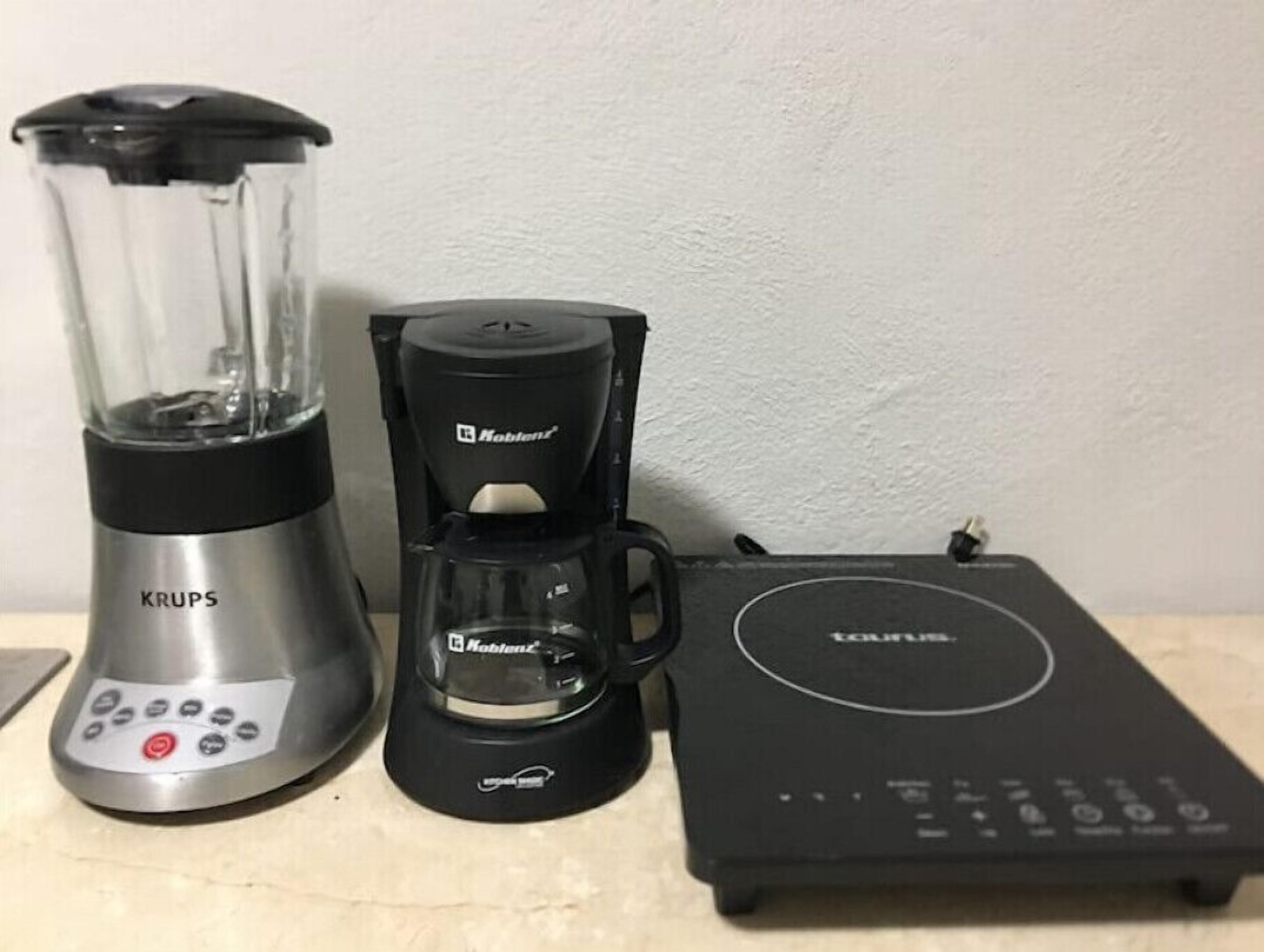 KRUPS-tehosekoitin, Hobart-kahvinkeitin ja kannettava Toshiba-laite pöydällä.