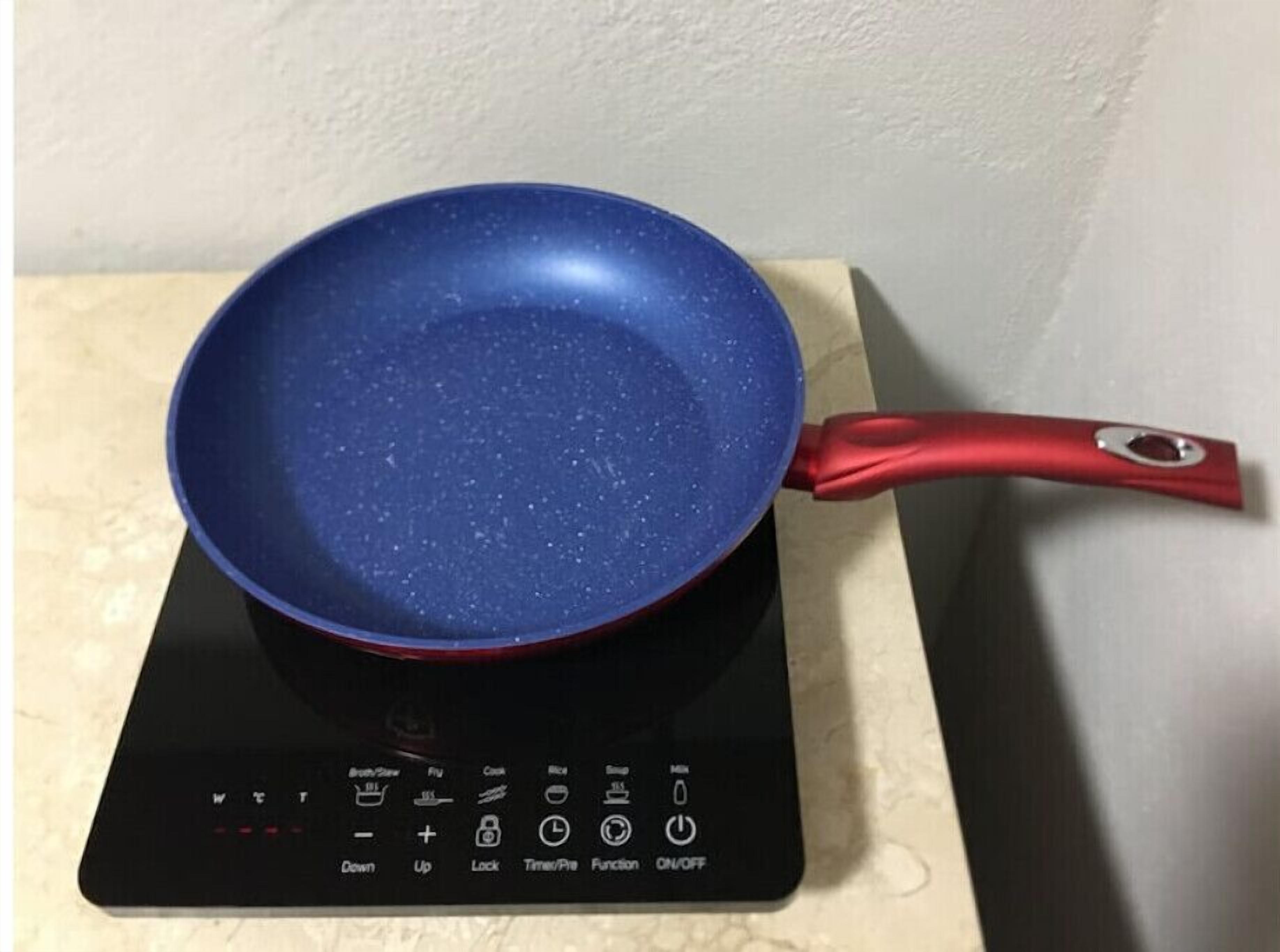 Eine blaue Bratpfanne auf einem Induktionskochfeld mit einem roten Griff.