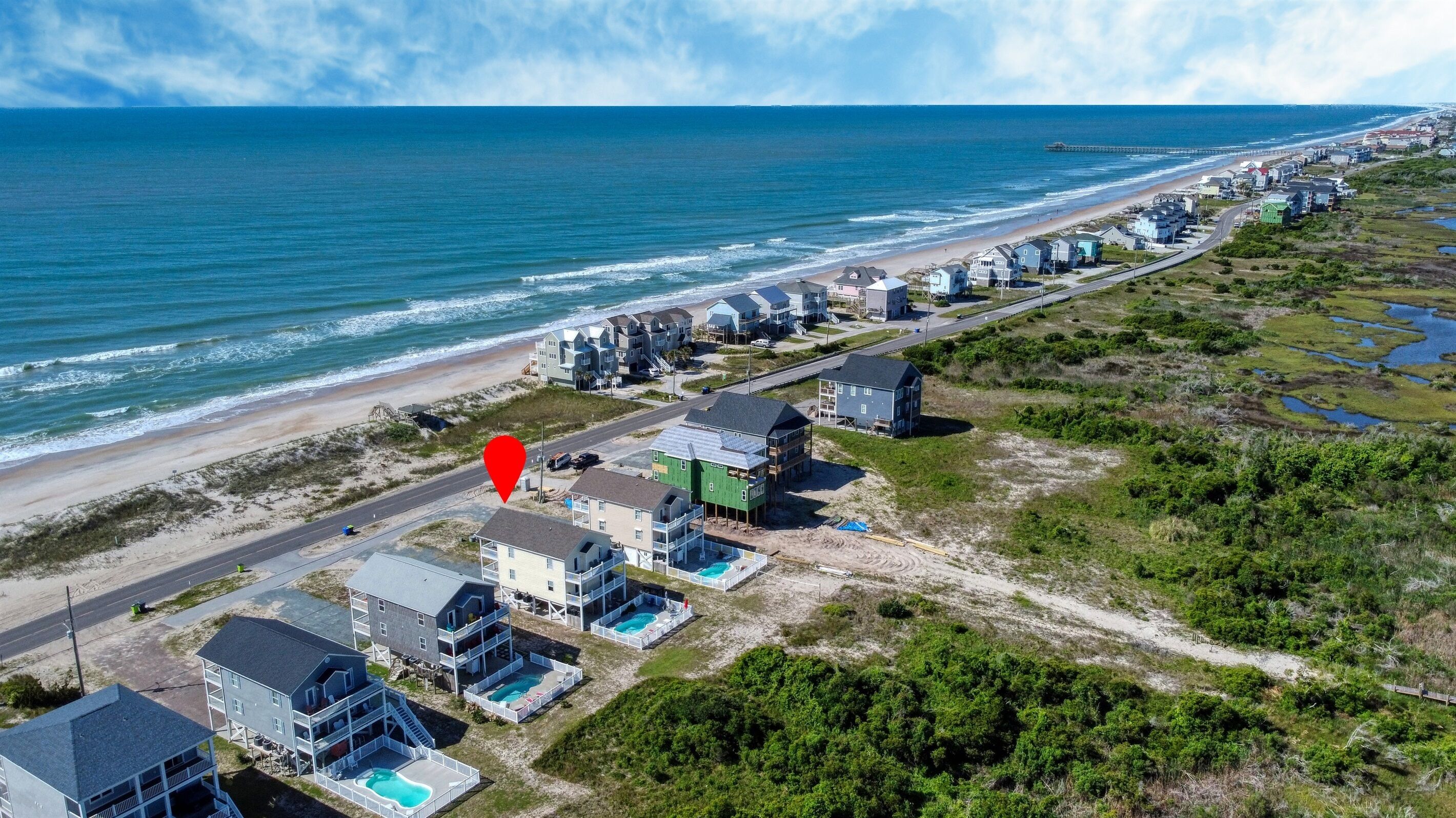 Vista aérea de una zona residencial costera con casas, una playa y un muelle.
