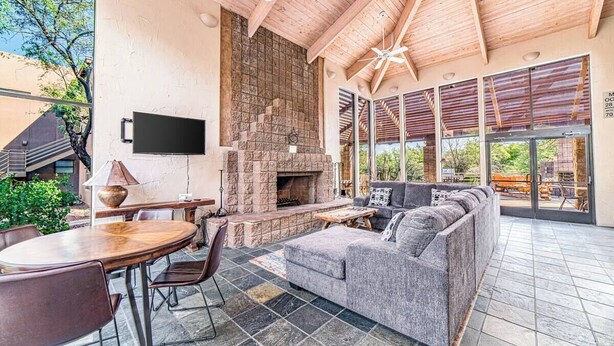 An outdoor living area with a stone fireplace, a sofa, and a dining table. - Canyon Vista 🌵INCREDIBLE VIEWS- Remodeled, Heated Pool, Spa, Hiking, Gym (Tucson)