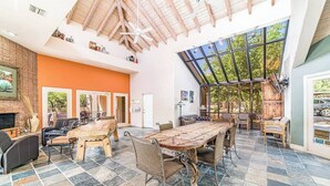 A spacious room with a large wooden dining table, multiple chairs, a fireplace, and a high ceiling with exposed beams. - Canyon Vista 🌵INCREDIBLE VIEWS- Remodeled, Heated Pool, Spa, Hiking, Gym (Tucson)