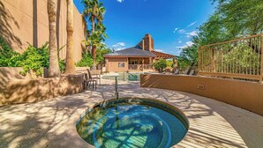 A pool area with a circular hot tub, palm trees, and a building with a sloped roof in the background. - Canyon Vista 🌵INCREDIBLE VIEWS- Remodeled, Heated Pool, Spa, Hiking, Gym (Tucson)