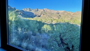 A window view of a desert landscape with mountains in the background. - Canyon Vista 🌵INCREDIBLE VIEWS- Remodeled, Heated Pool, Spa, Hiking, Gym (Tucson)