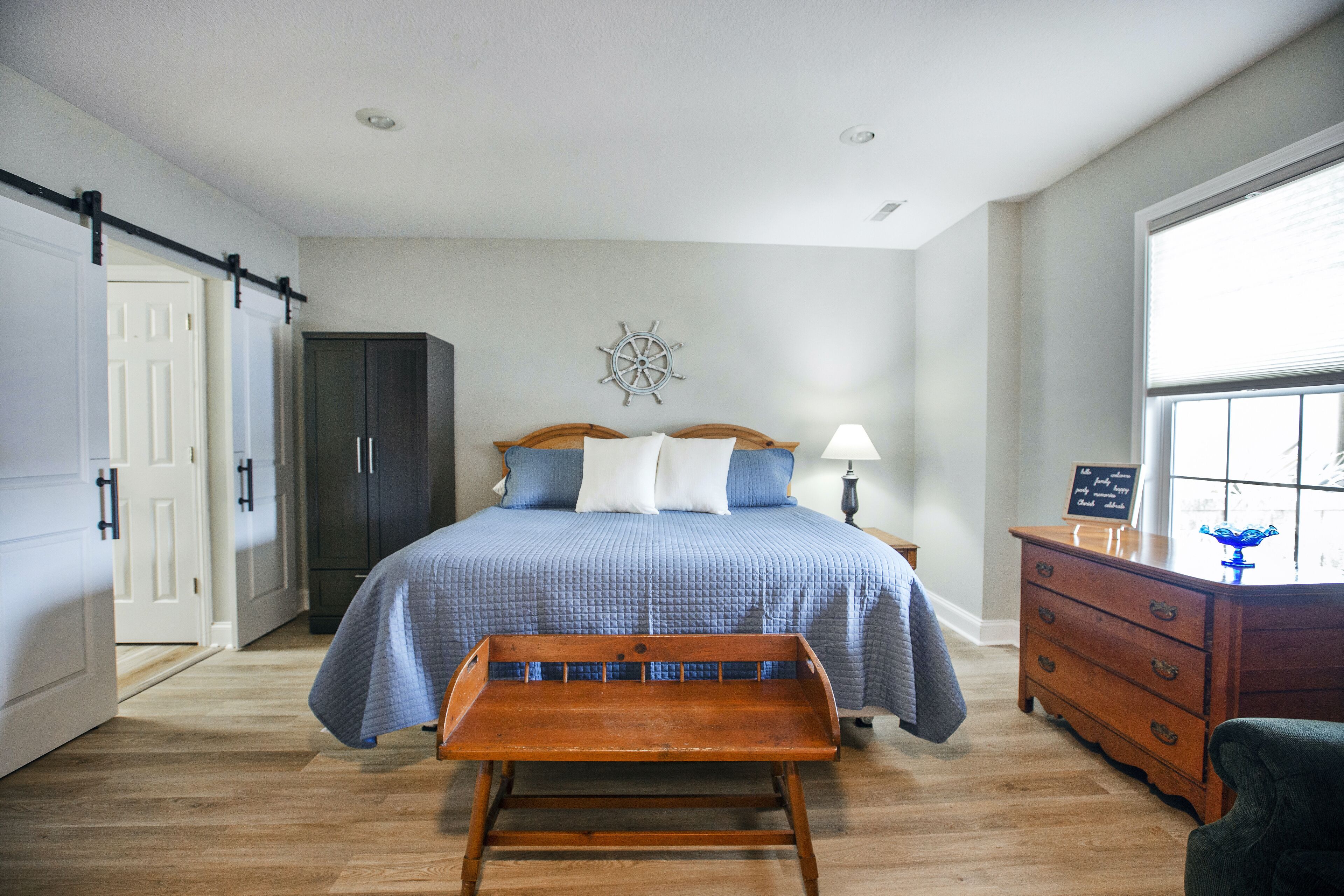 Une chambre à coucher comprenant un lit, un banc en bois, une commode et un élément décoratif mural.