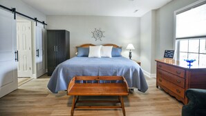 Ein Schlafzimmer mit einem Bett, einer hölzernen Bank, einem Schminktisch und einer Wanddekoration.