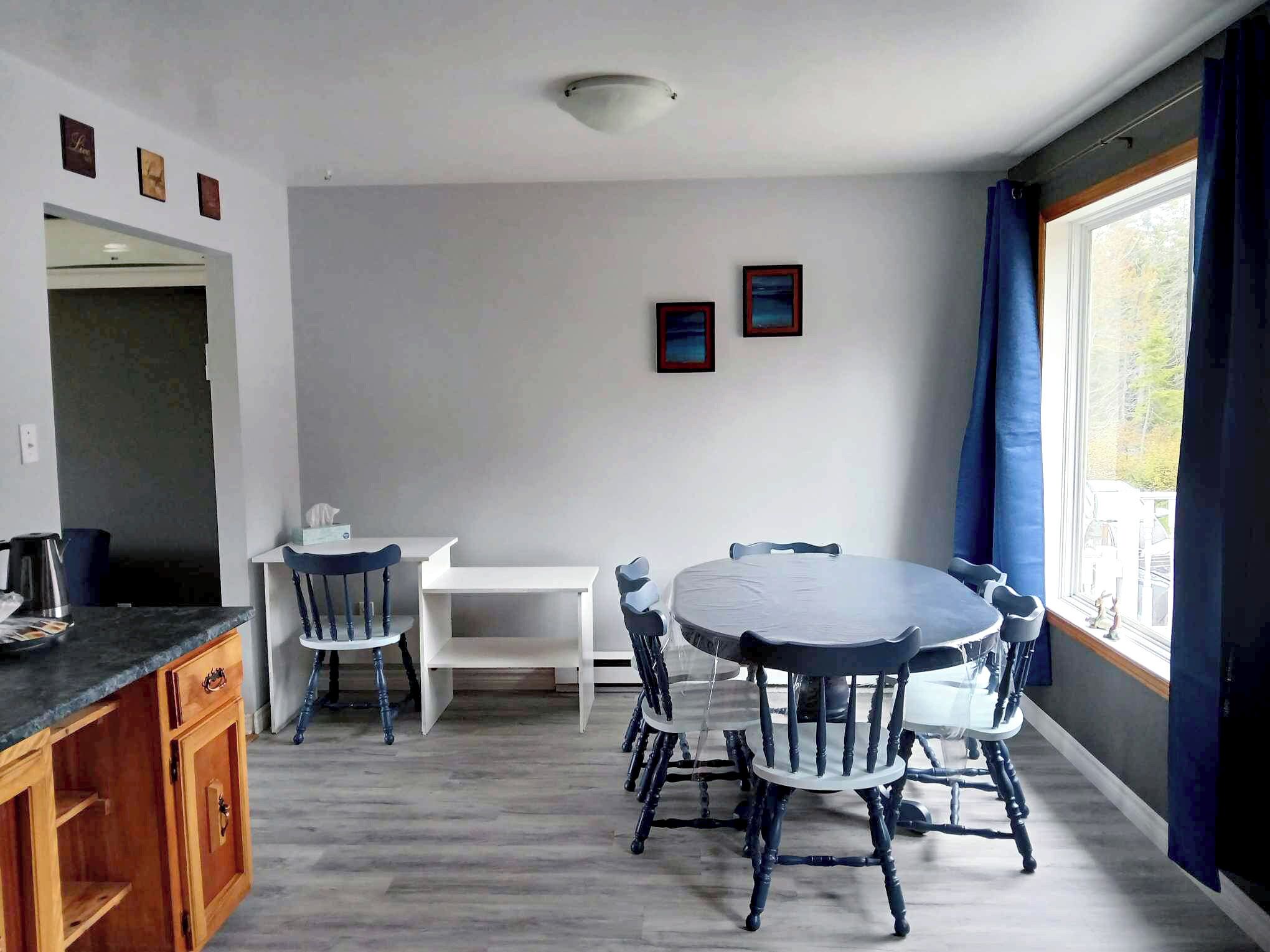Un coin repas avec une table ronde et des chaises, un meuble blanc et une fenêtre avec des rideaux.