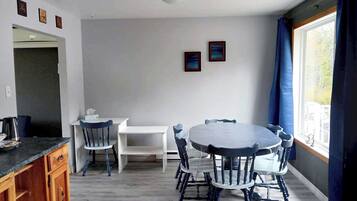Un coin repas avec une table ronde et des chaises, un meuble blanc et une fenêtre avec des rideaux.