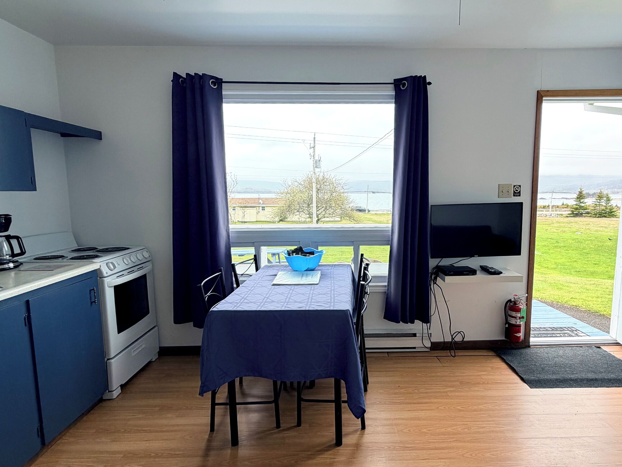 A compact kitchen with a stove, dining table, and a TV.