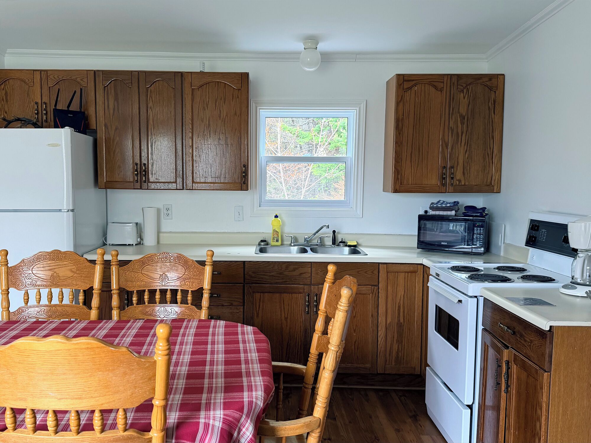A kitchen with wooden cabinets, a white refrigerator, a microwave, a stove, and a dining table with chairs.