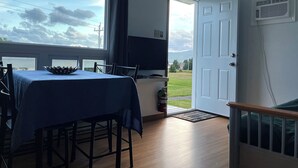 Un comedor con una mesa dispuesta para cuatro personas, un televisor y una puerta que da al exterior.