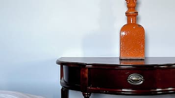A wooden side table with a drawer and a decorative bottle on top.