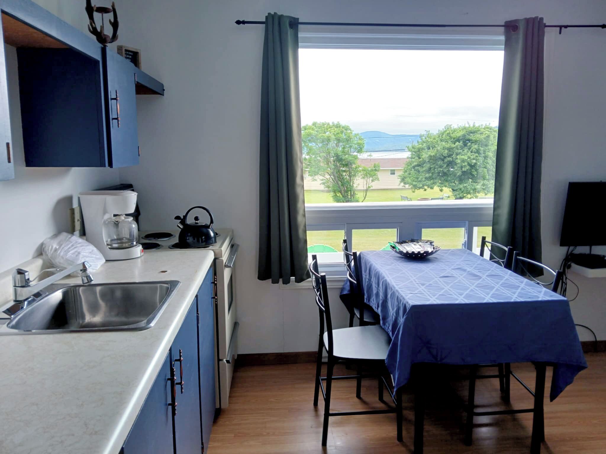 A kitchen with a dining table, a coffee maker, and a view of the outdoors.
