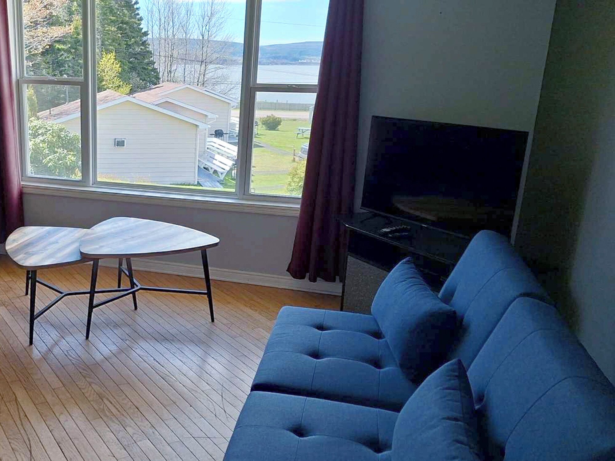 A living room with a blue sofa, a small white table, and a TV on a stand.
