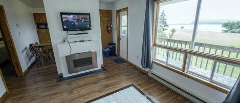 Una sala de estar con chimenea, televisor y un ventanal con vistas al exterior.