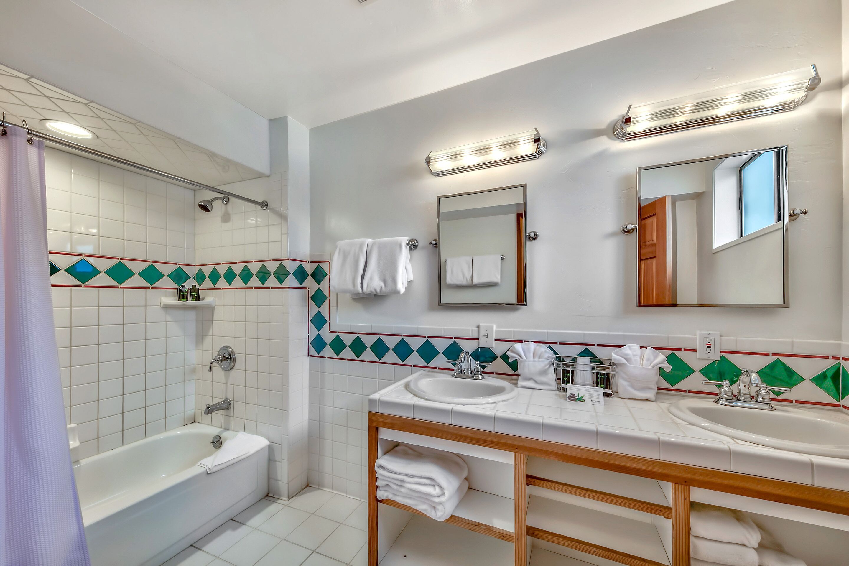 A modern bathroom with a bathtub, two sinks, a vanity, and a large mirror.