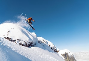 Un snowboardeur effectuant un saut au-dessus d’une montagne enneigée.