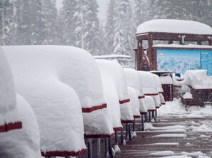 File di panche innevate con una struttura in legno sullo sfondo.