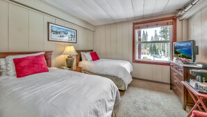 A hotel room with two beds, a TV, a desk, and a window with a view of trees. - Northern  Twin  Room (Norden)