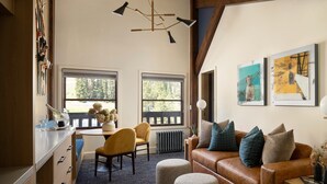 A cozy living room with a brown leather sofa, ottomans, a dining table with chairs, and a fireplace. - Deluxe  Suite   Room (Norden)