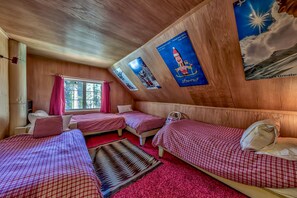 A room with three beds, a window, and wooden walls.