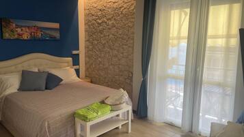 A bedroom with a bed, a stone accent wall, a window with curtains, and a painting on the wall.